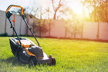 Photo of a modern electric lawn mower standing on a backyard lawn near a house